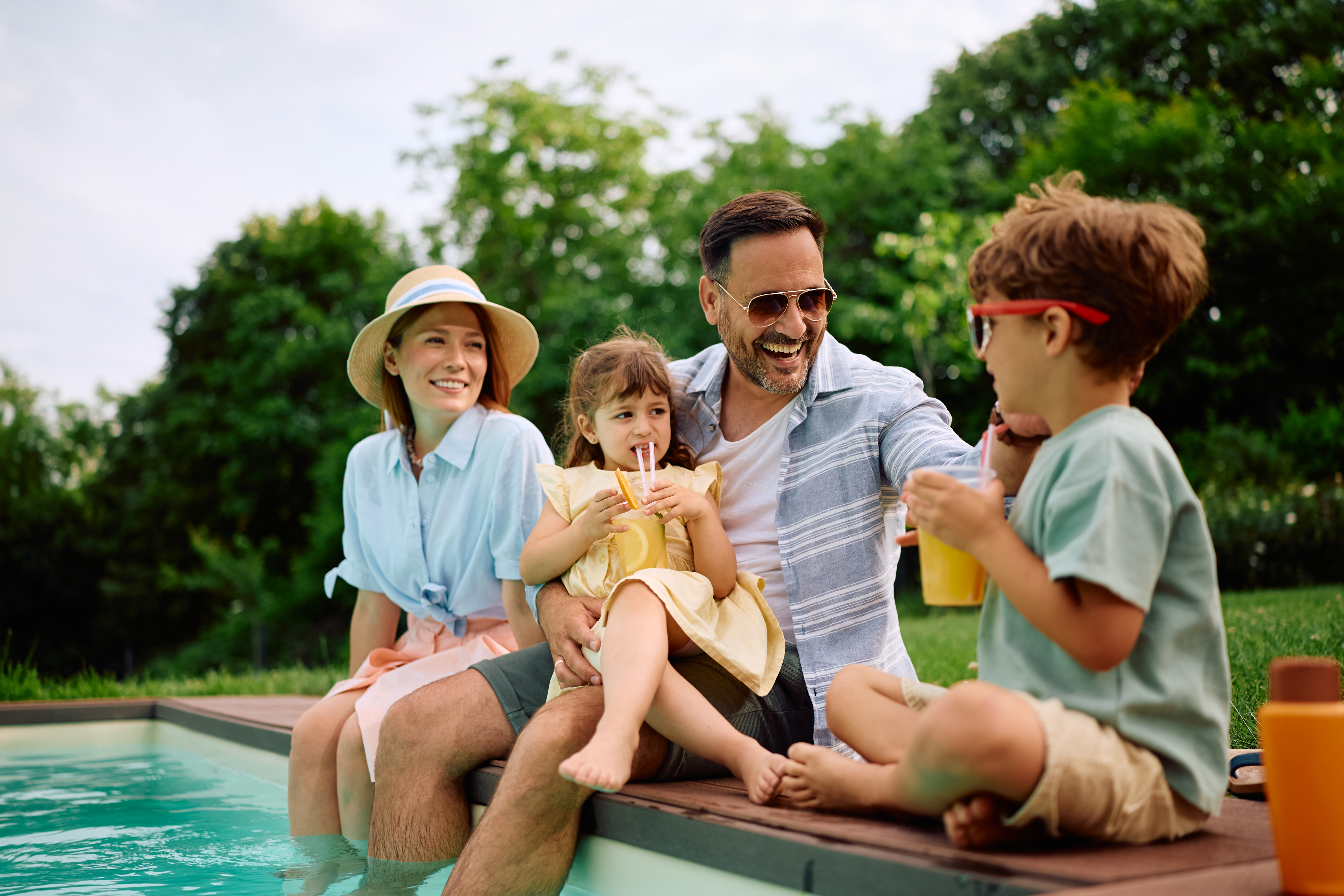 Happy family relaxing at pool side during their summer vacation.