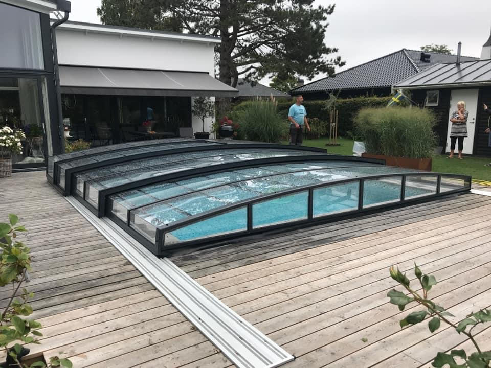 Swimming pool covered with blue protective tarp, surrounded by artificial grass and fence in a backyard residential setting